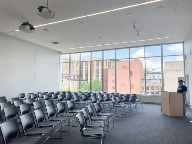 rows of chairs in front of large window facing a person standing at a podium