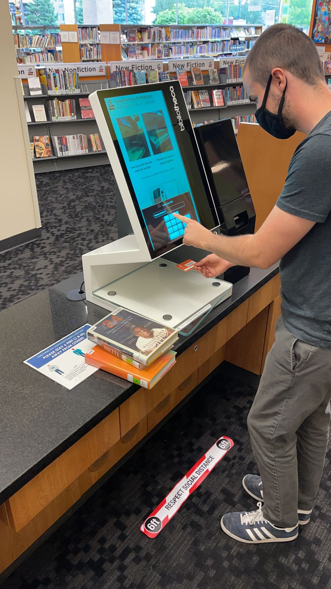 A patron checks out using a self-check machine at Goodman South Madison Library