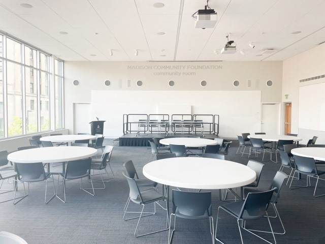 Round tables with chairs facing a large stage with seating