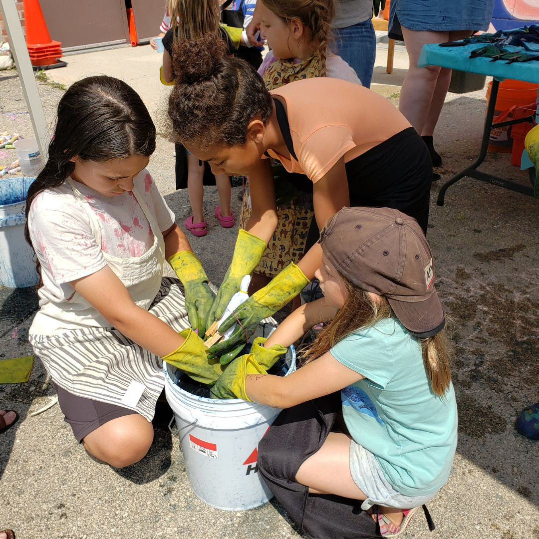 Kids reaching into a bucket of indigo dye during an Arts in the Alley event Kids reaching into a bucket of indigo dye during an Arts in the Alley event