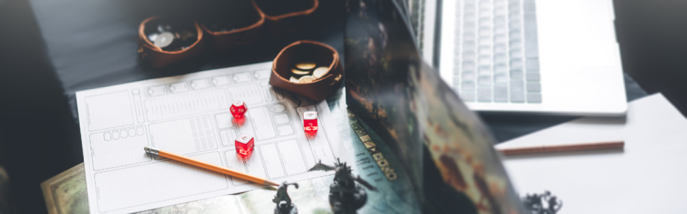 Dungeons and Dragons game pieces and characters on a map with a laptop