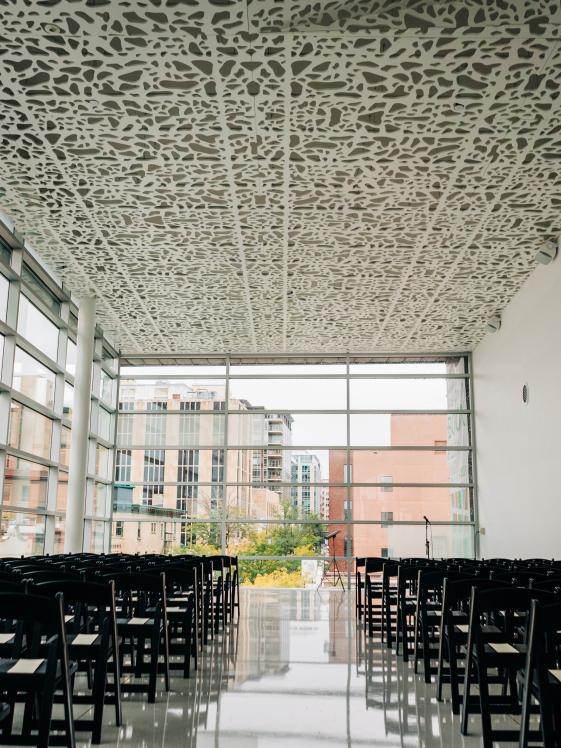 Madison Room Wedding.jpg Floor to ceiling window room with black chairs in rows forming a center aisle