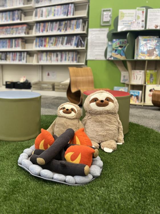 Meadowridge Library Play Space features Treehouse vibe with reading buddies, grass, and fake campfire