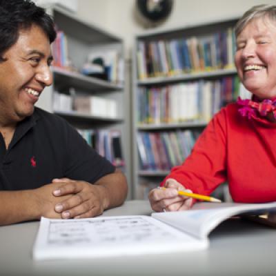 an adult tutoring another adult in a library