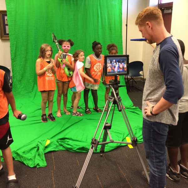 group of girls recording a music video at the library in front of a green screen