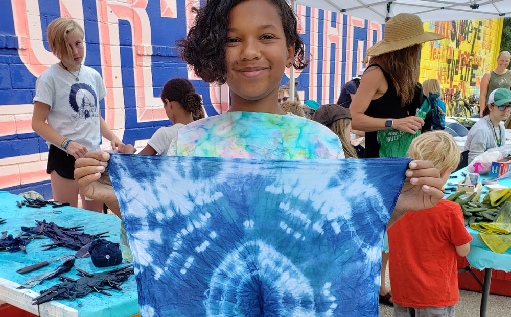 Young kid holding cloth dyed with indigo dye during an Arts in the Alley event