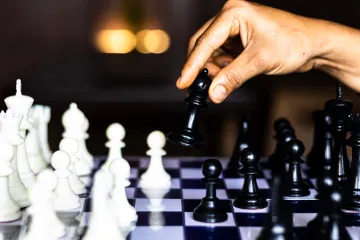 Hand moving a chess piece on a board full of pieces