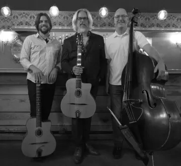 A black-and-white photo of the three members of Caravan. Two of the men each hold a guitar and the third stands next to his upright bass. A black-and-white photo of the three members of Caravan. Two of the men each hold a guitar and the third stands next to his upright bass.