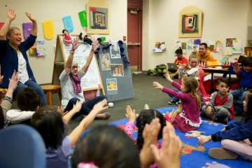 A happy group of children at a storytime with smiling librarians